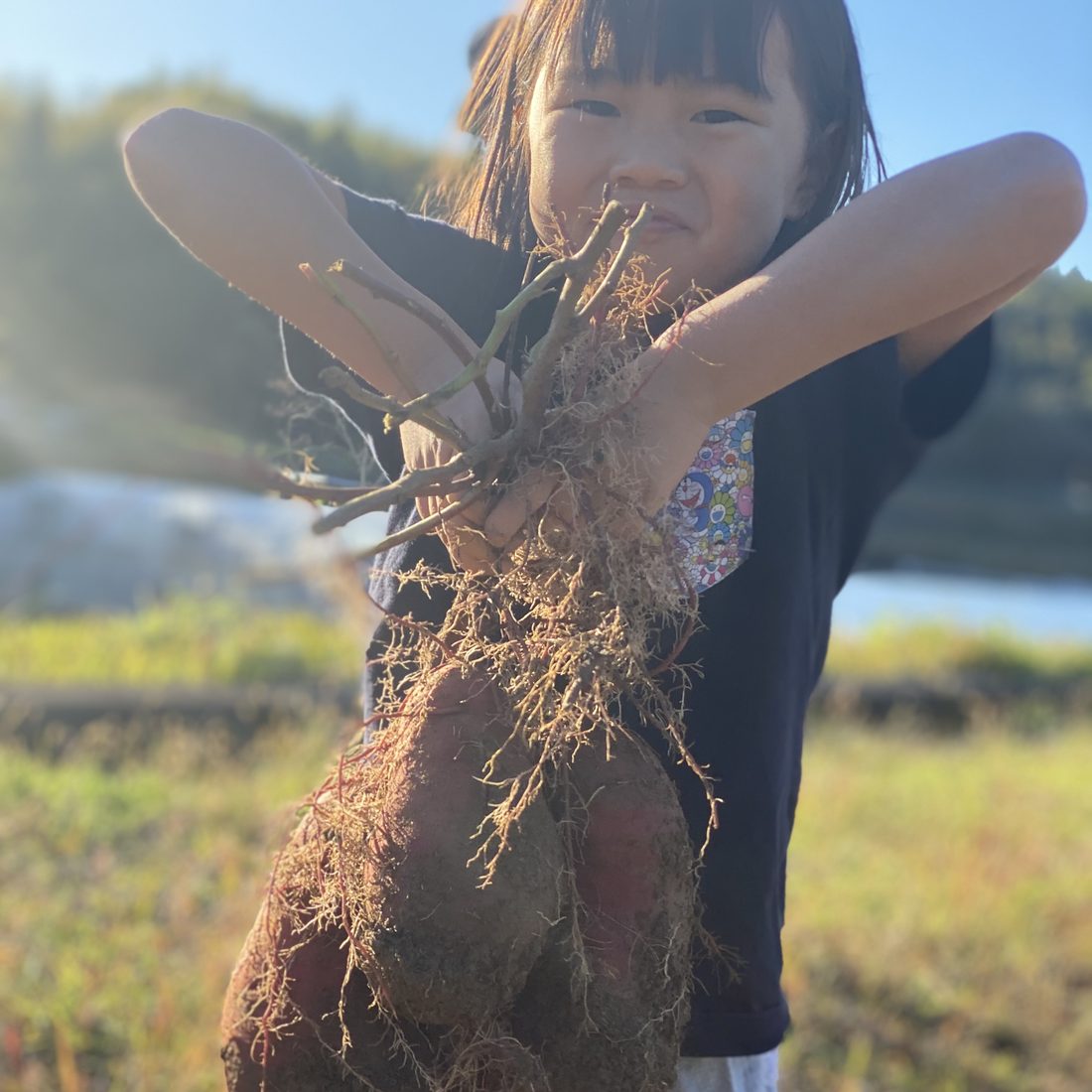 収穫した野菜を掲げる子ども